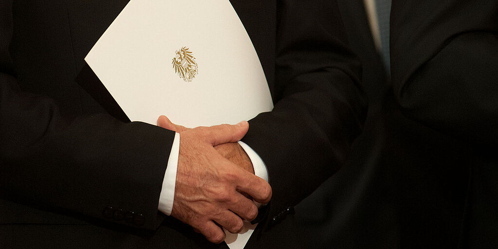 Person hält eine Mappe mit dem Amtswappen darauf