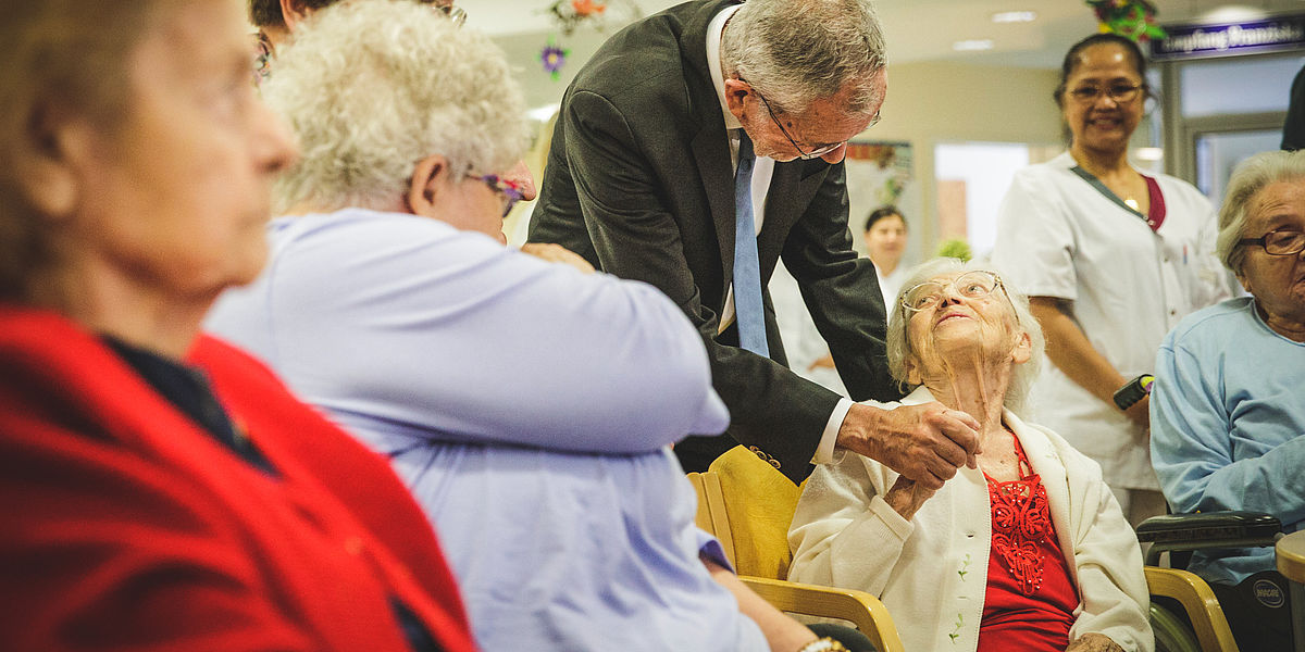 Alexander Van der Bellen schüttelt einer älteren Person die Hand